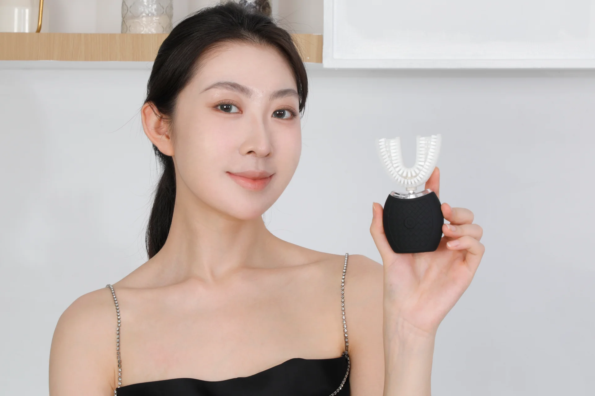 Woman holding a black compact TB-01 toothbrush